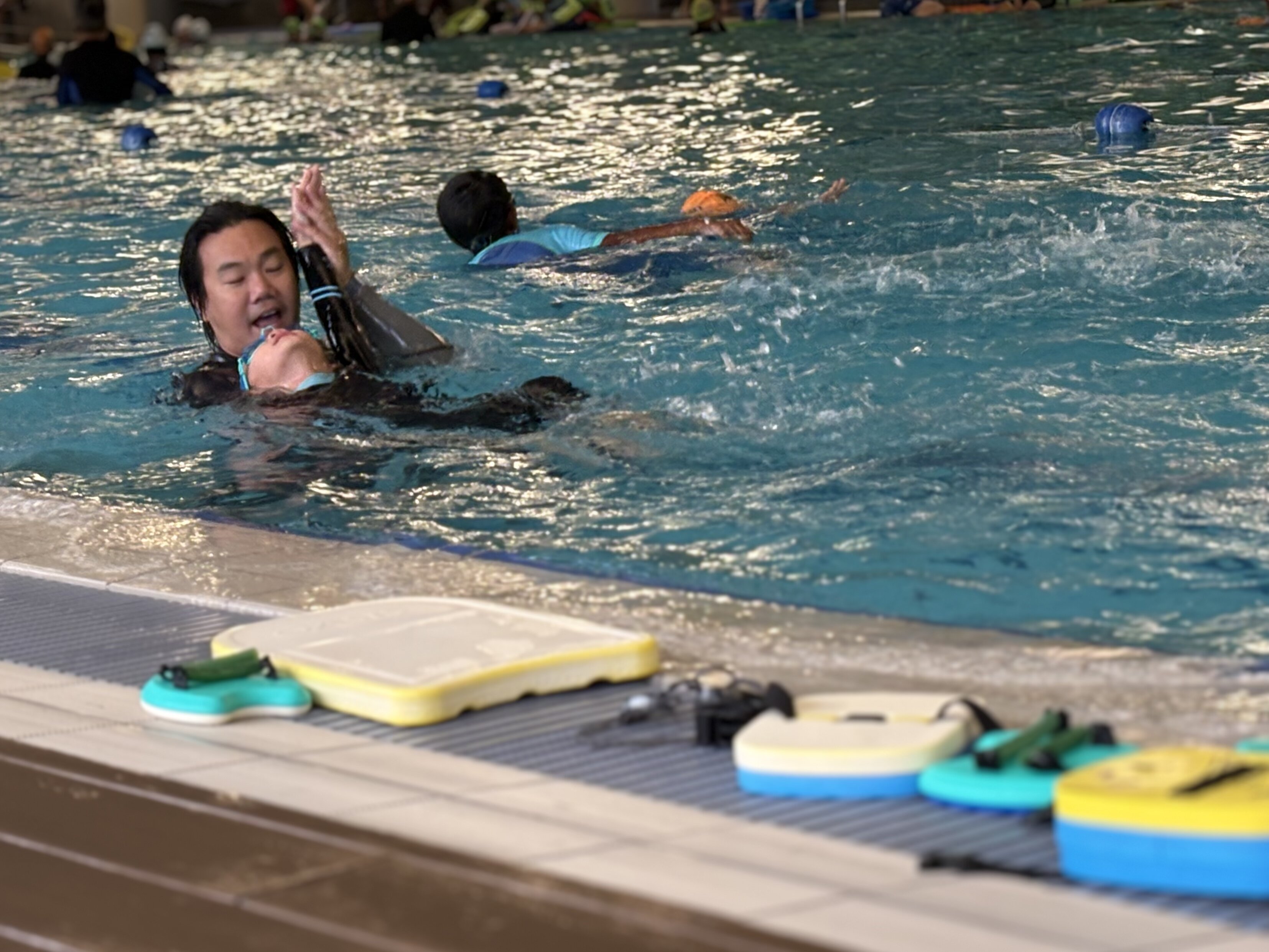 Coach correcting student swimming technique in the pool