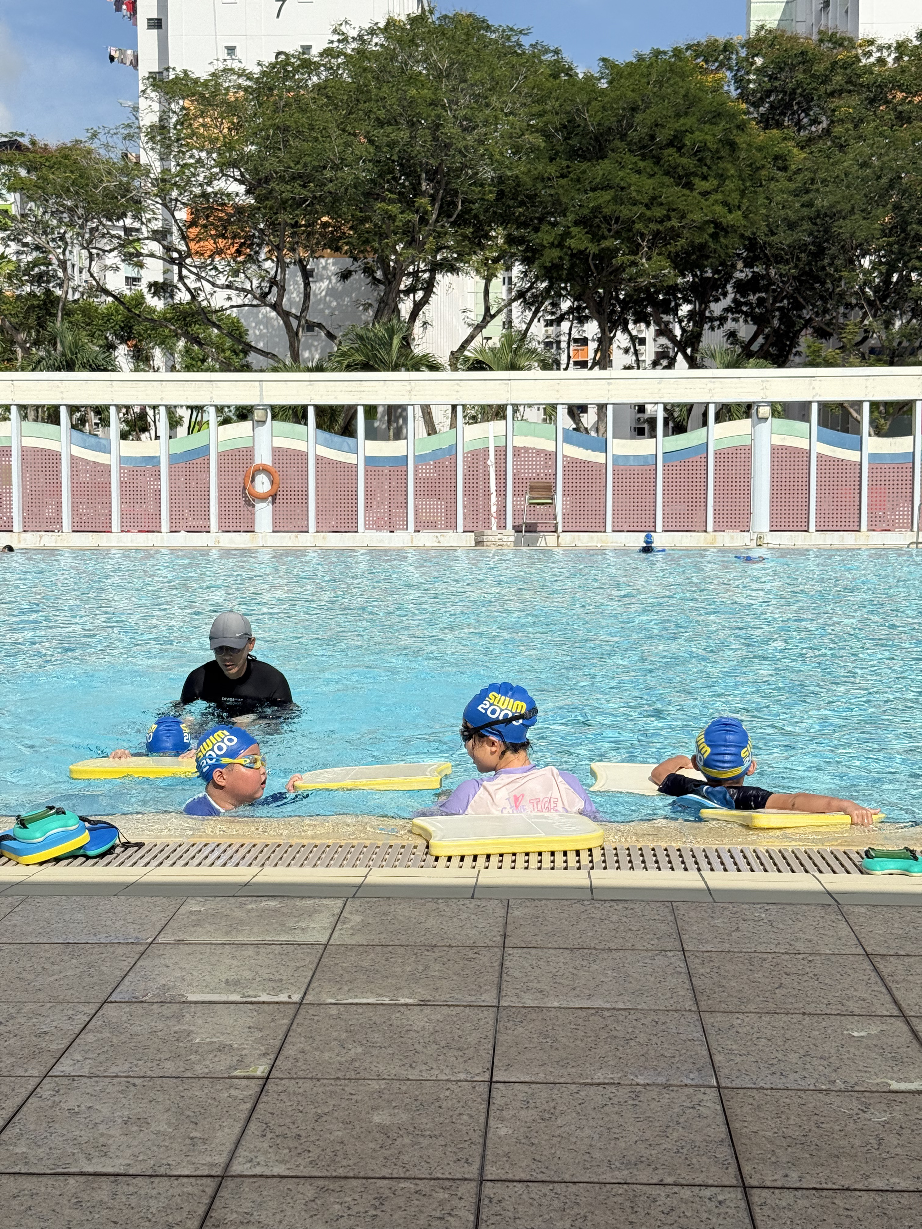 Coach correcting student technique during kids swimming lesson
